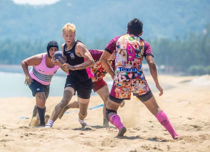 Photo of James playing rugby at beach